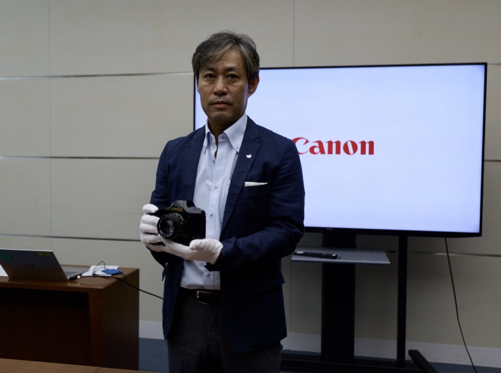 An excutive holds a Canon T-90 in his glvoed hands. 